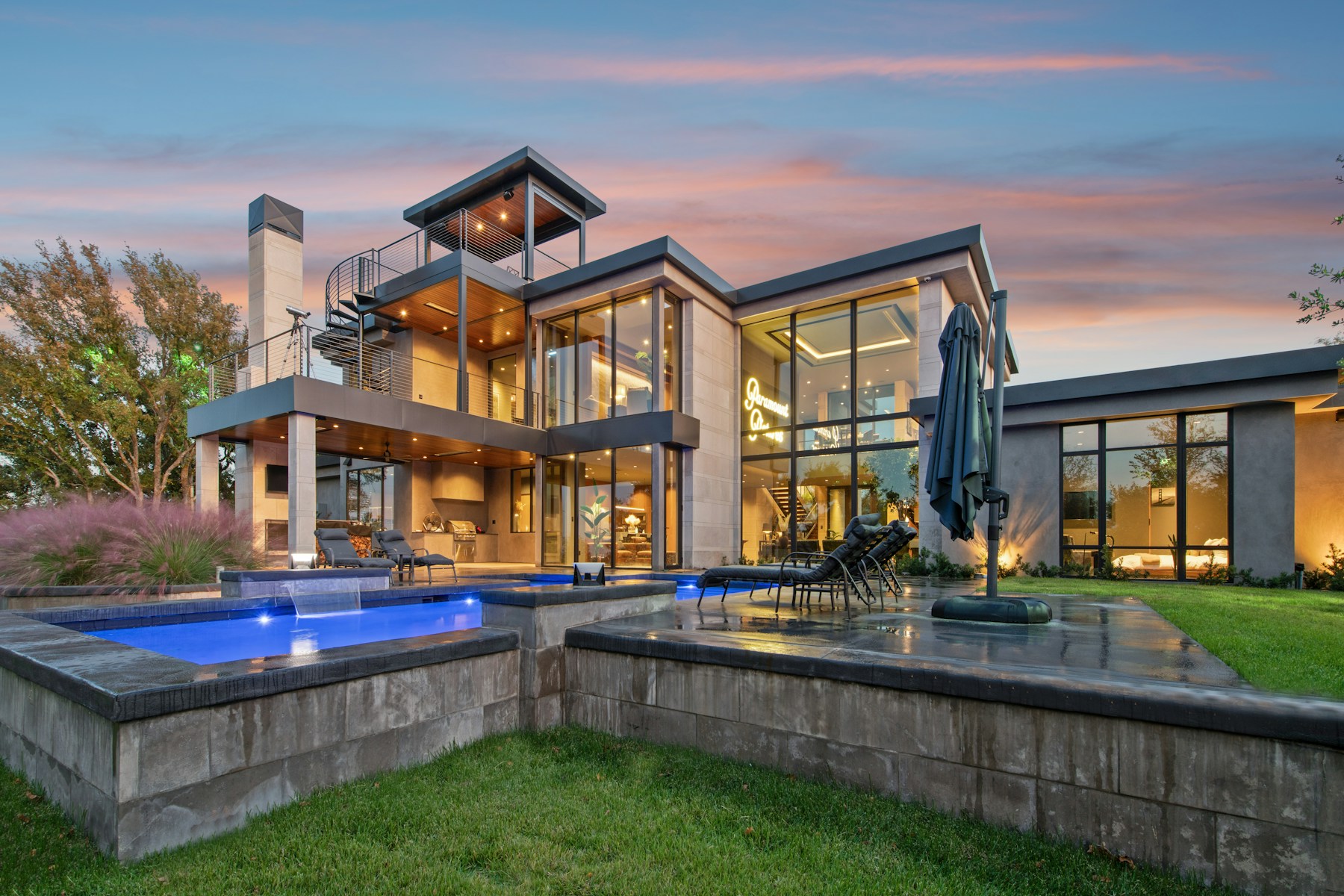 Contemporary building structure by LHS CONTRACTING LLP with floor-to-ceiling glass, warm interior lighting and landscaped terraces